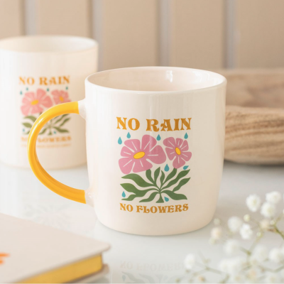 Caneca branca com pega amarela e texto decorativo com flores.
