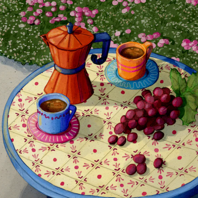 Mesa redonda azul com cafeteira italiana laranja, duas chávenas de café coloridas e cacho de uvas roxas em relva com flores rosa