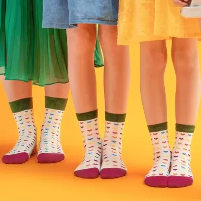 Pares de meias coloridas com padrão de carinhas sorridentes em fundo laranja