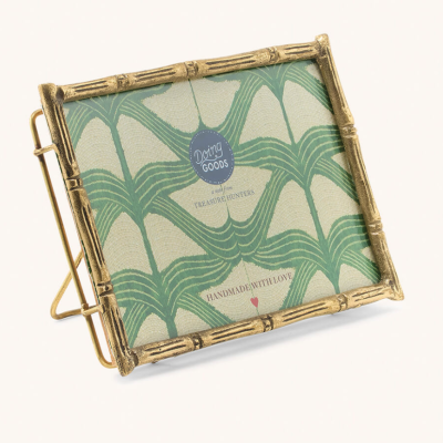 Moldura de metal dourada com padrão de bambu e suporte, com imagem decorativa verde e texto