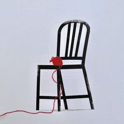 Cadeira preta com novelo de lã vermelho no assento sobre fundo branco