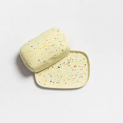 Caixa e prato de sabonete creme com pintas coloridas em fundo branco