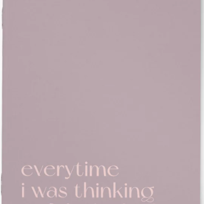 Caderno lavanda com texto em branco 'Notebook of' e frase em inglês.