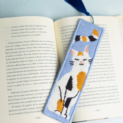 Marcador de livro bordado com desenho de gato colorido sobre livro aberto