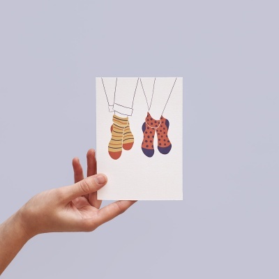 Cartão com desenho de pernas com meias coloridas segurado por mão