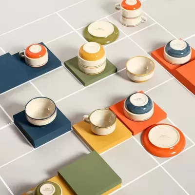 Recipientes pequenos de cerâmica coloridos sobre placas quadradas coloridas