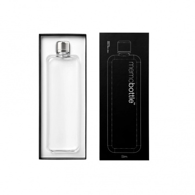 Frasco de vidro transparente com tampa prateada em embalagem preta com texto memo bottle