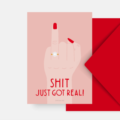 Cartão rosa com mão a mostrar dedo do meio, texto SHIT JUST GOT REAL!, e envelope vermelho
