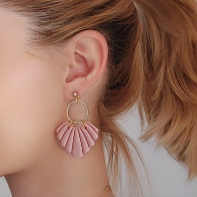 Brinco pendente dourado com peças rosa em formato leque num ouvido