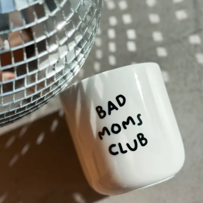 Caneca branca com texto preto BAD MOMS CLUB junto a globo espelhado