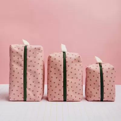 Três necessaires rosa com padrão de flores e fecho verde em diferentes tamanhos