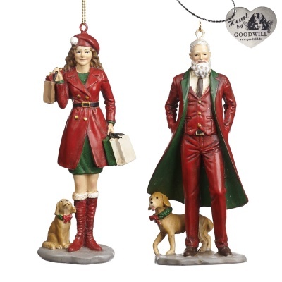 Duas figuras decorativas de Natal: mulher e homem com casacos vermelhos e verdes, cada um com cão pequeno, penduradas.