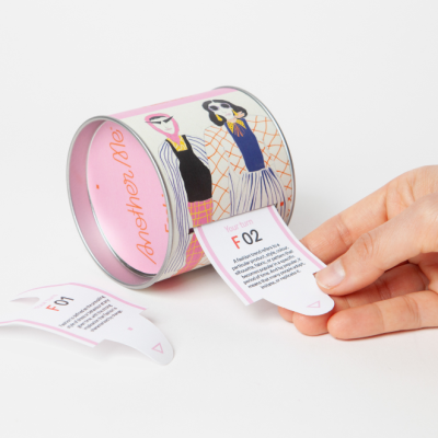 Lata metálica decorada com ilustração de figuras femininas e papeis destacáveis com texto e código.