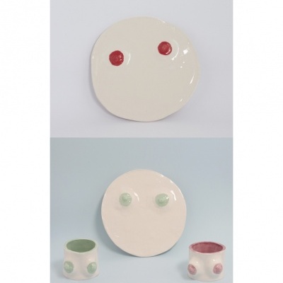 Pratos e tigelas cerâmicas brancas com pontos coloridos vermelho e verde no fundo claro