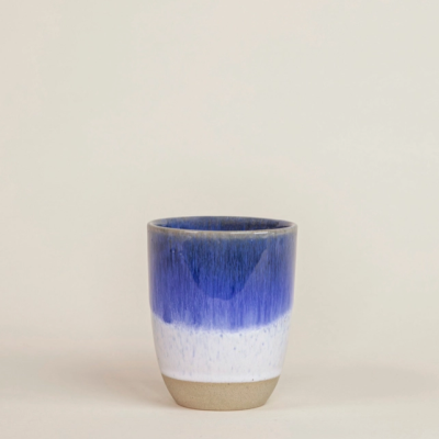 Copo cerâmico azul, branco e bege sobre superfície clara