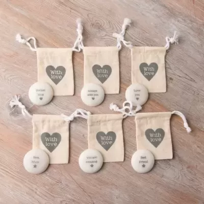 Pedras decorativas com mensagens e saquinhos de tecido com cordão