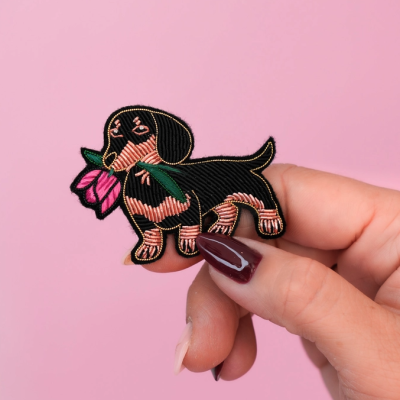 Aplique bordado cão dachshund com flor em mão sobre fundo rosa