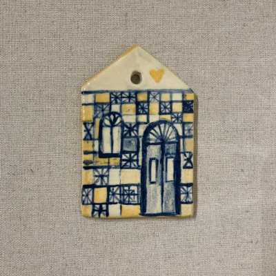 Objeto decorativo em cerâmica em forma de casa com padrões de azulejo amarelo e azul