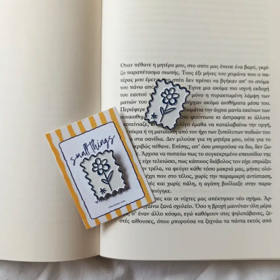 Autocolante de flor em papel transparente sobre livro aberto com texto em grego