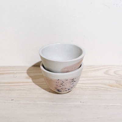 Dois pequenos recipientes de cerâmica empilhados em madeira clara