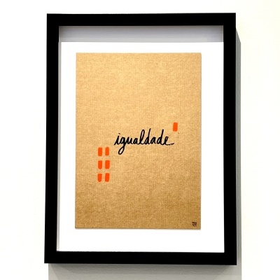 Quadro com palavra igualdade escrita em papel castanho dentro de moldura preta