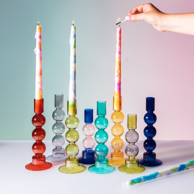 Castiçais de vidro colorido com velas multicoloridas e mão a acender vela