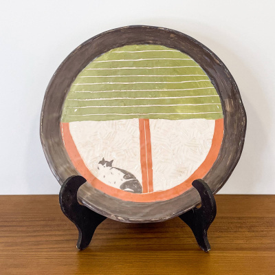 Prato decorativo em cerâmica com padrão colorido num suporte preto