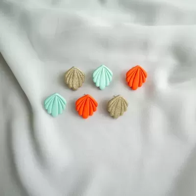 Seis patches em forma de concha em azul claro, laranja e castanho claro sobre tecido branco