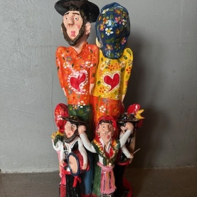 Estátua colorida com cinco figuras humanas em roupas tradicionais sobre superfície escura