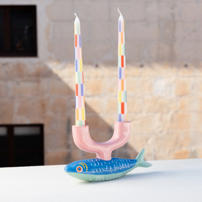 Castical decorativo em forma de peixe azul com suporte rosa e duas velas listradas