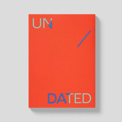 Caderno capa dura vermelha com texto UN DATED em relevo azul e cinza