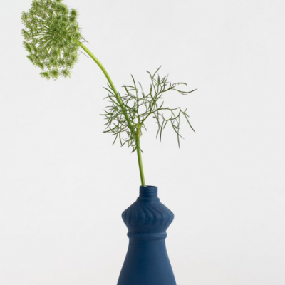 Vaso azul em cerâmica com planta e flor branca sobre fundo branco