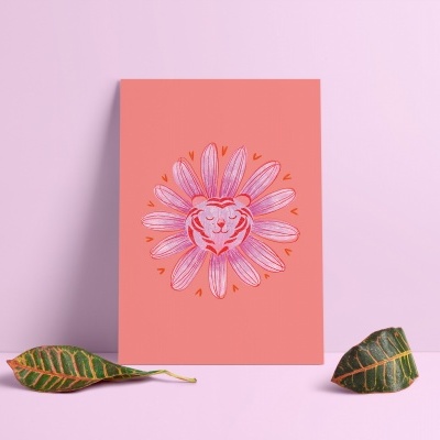 Cartão cor-de-rosa com ilustração de flor e rosto de leão, sobre superfície cor-de-rosa com duas folhas verdes ao lado.