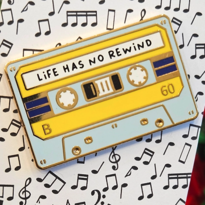Alfinete cassete amarelo com texto LiFE HAS NO REWIND