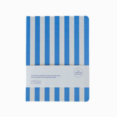 Planner com capa azul e branca listrada com faixa de papel branca e texto