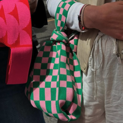 Bolsa quadriculada verde e rosa sendo segurada por pessoa