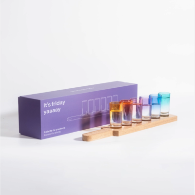 Seis copos de shot coloridos com suporte de madeira e caixa roxa com texto