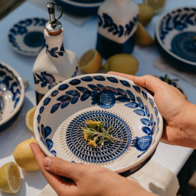 Conjunto de loiça branca decorada com padrão azul, prato fundo e recipiente com tampa, limões na mesa