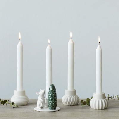 Conjunto de castiçais brancos com velas acesas, base com coelho e pinheiro, raminhos verdes