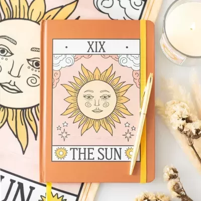 Caderno com ilustração do sol e texto THE SUN XIX com caneta dourada