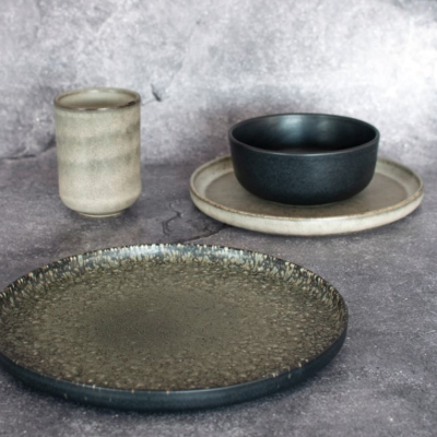 Conjunto de loiça com prato raso texturado, prato cinzento claro, tigela preta e copo cerâmico bege