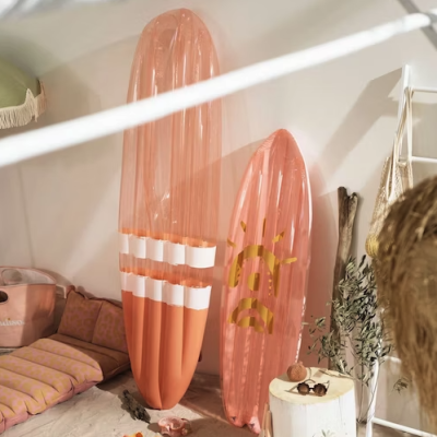 Duas pranchas de surf insufláveis cor de rosa apoiadas numa parede interior de sala decorada