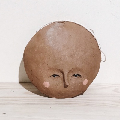 Escultura redonda em terracota com rosto pintado