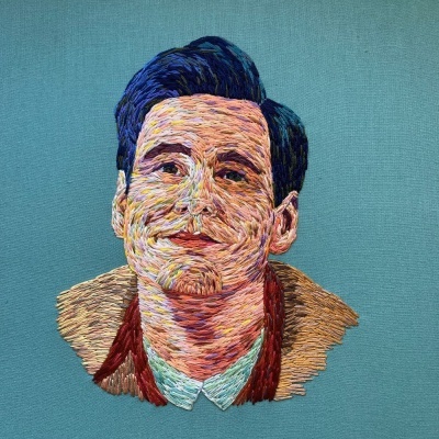 Retrato bordado colorido de homem com cabelo escuro em tecido azul