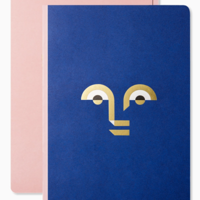 Dois cadernos, azul com rosto dourado e cor-de-rosa