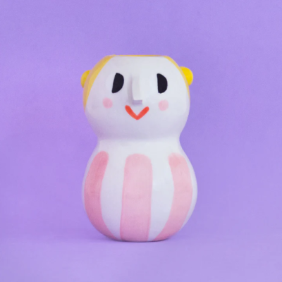 Boneco cerâmico decorativo colorido com riscas rosa e branco em fundo roxo