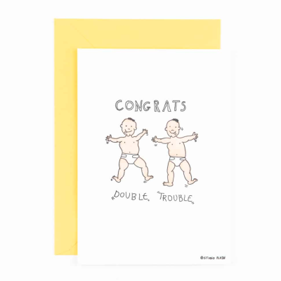 Cartão com desenho de dois bebés de fralda e texto 'CONGRATS DOUBLE TROUBLE' com envelope amarelo.
