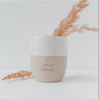 Vaso cerâmico branco e bege com texto HELLO NEW DAY e ramos secos
