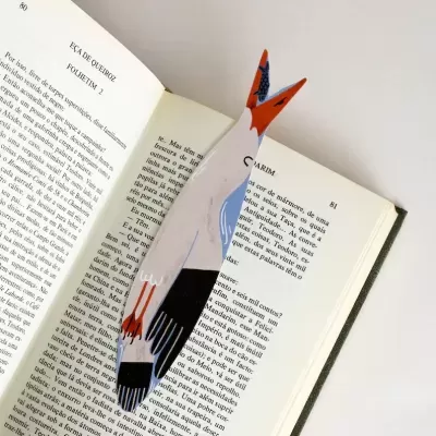 Marcador de livros em forma de pássaro colorido em madeira dentro de livro aberto
