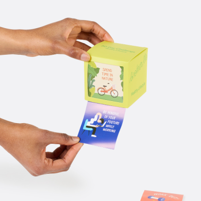 Mãos seguram cubo com mensagens sobre hábitos saudáveis e cartões coloridos com conselhos.